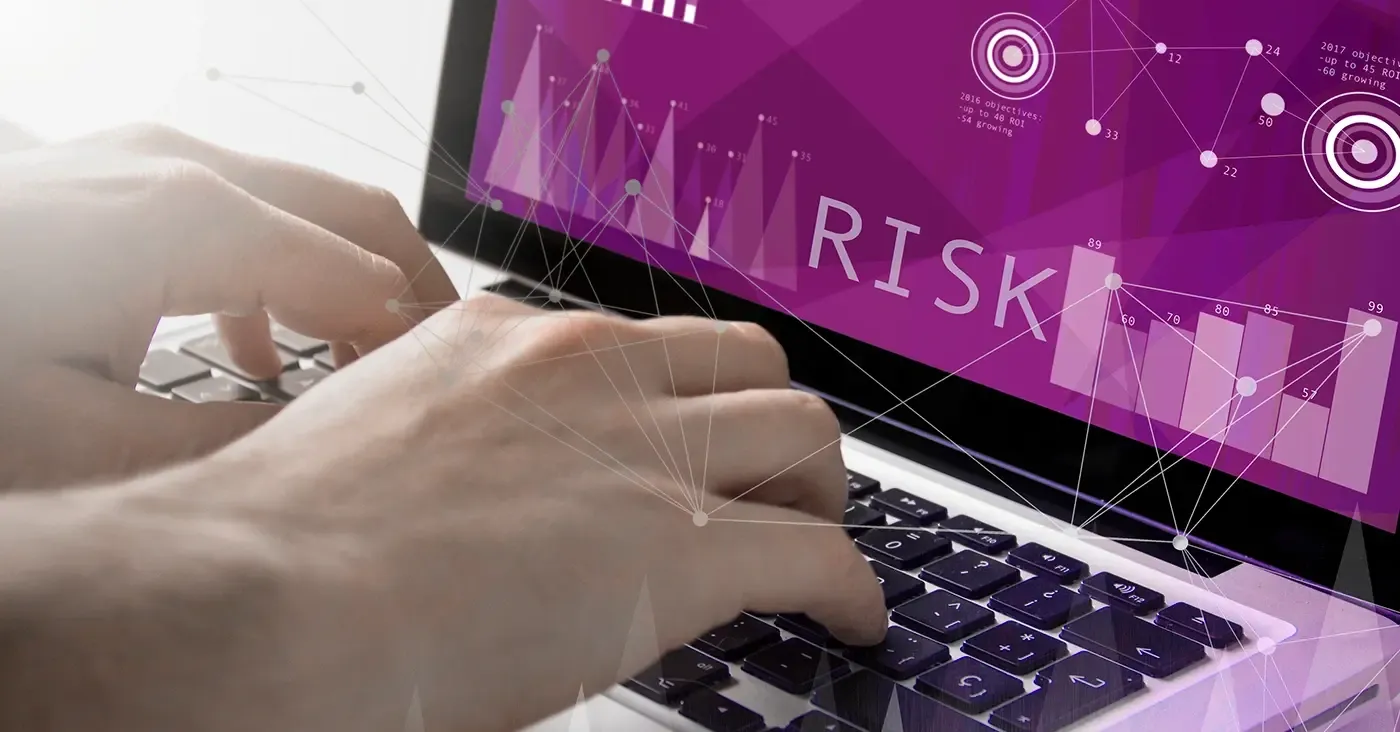 hands typing on laptop with risk warning