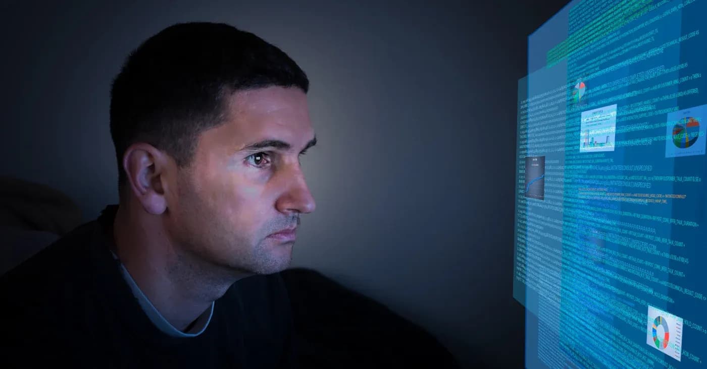 somber man looking at computer monitor