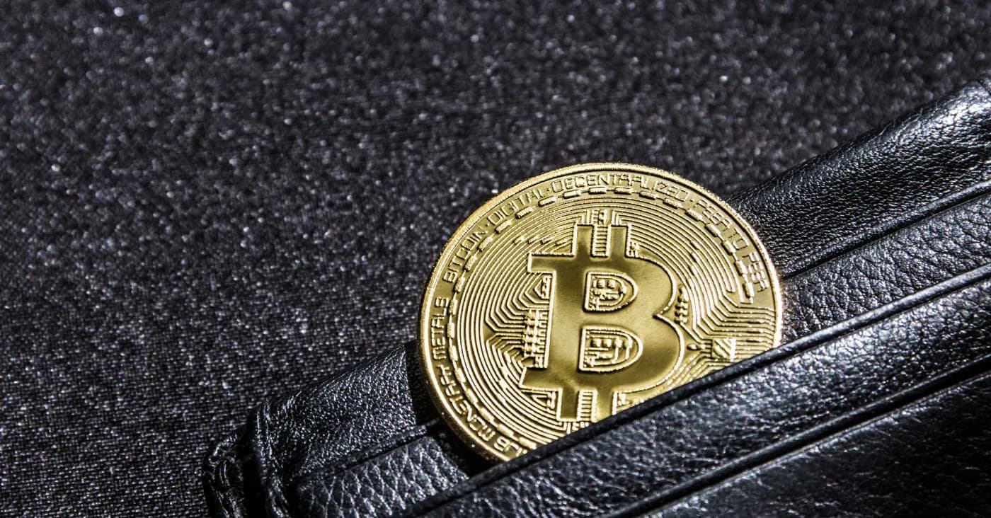 gold bitcoin sticking out of leather wallet