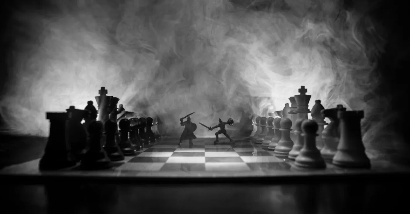 chessboard with two figures fighting between the set up pieces