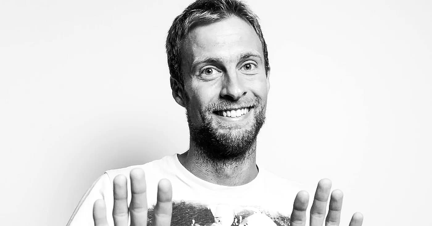 man smiling holding out hands as if to say back away camera