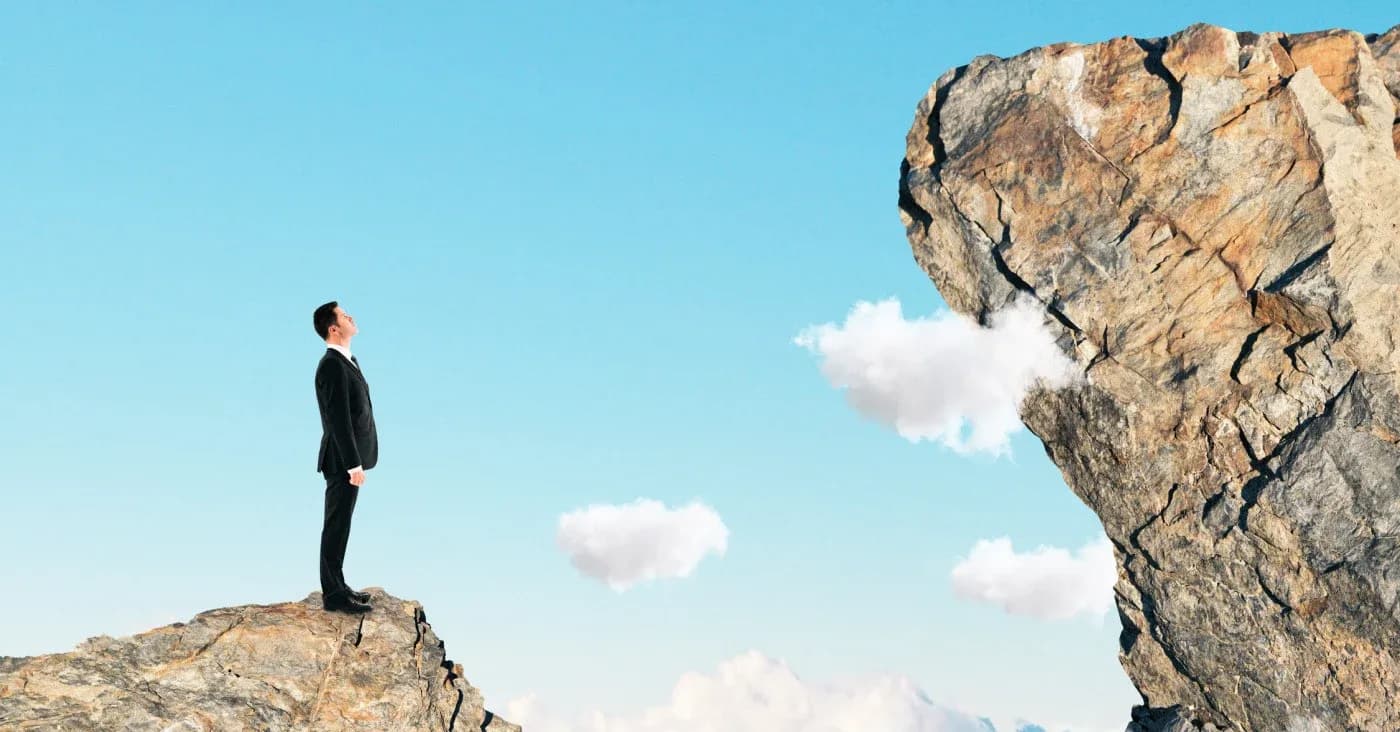 man in suit standing on cliff looking at sky