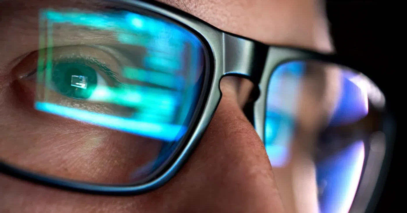 close-up of man wearing glasses with computer reflection