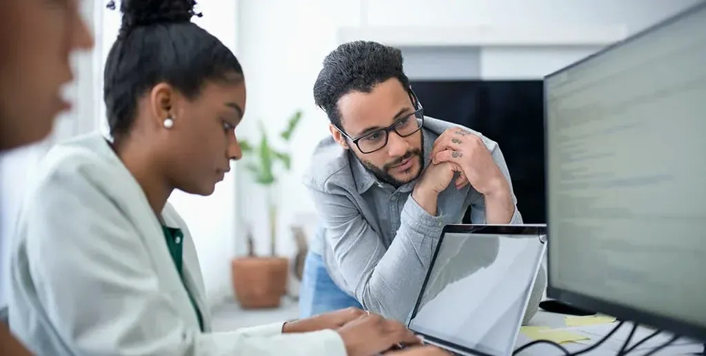man onlooking coworker's laptop