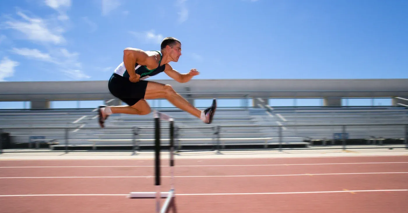 track athlete clearing a hurdle