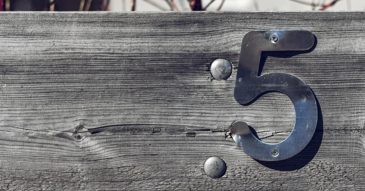 iron number five nailed to a wood plank