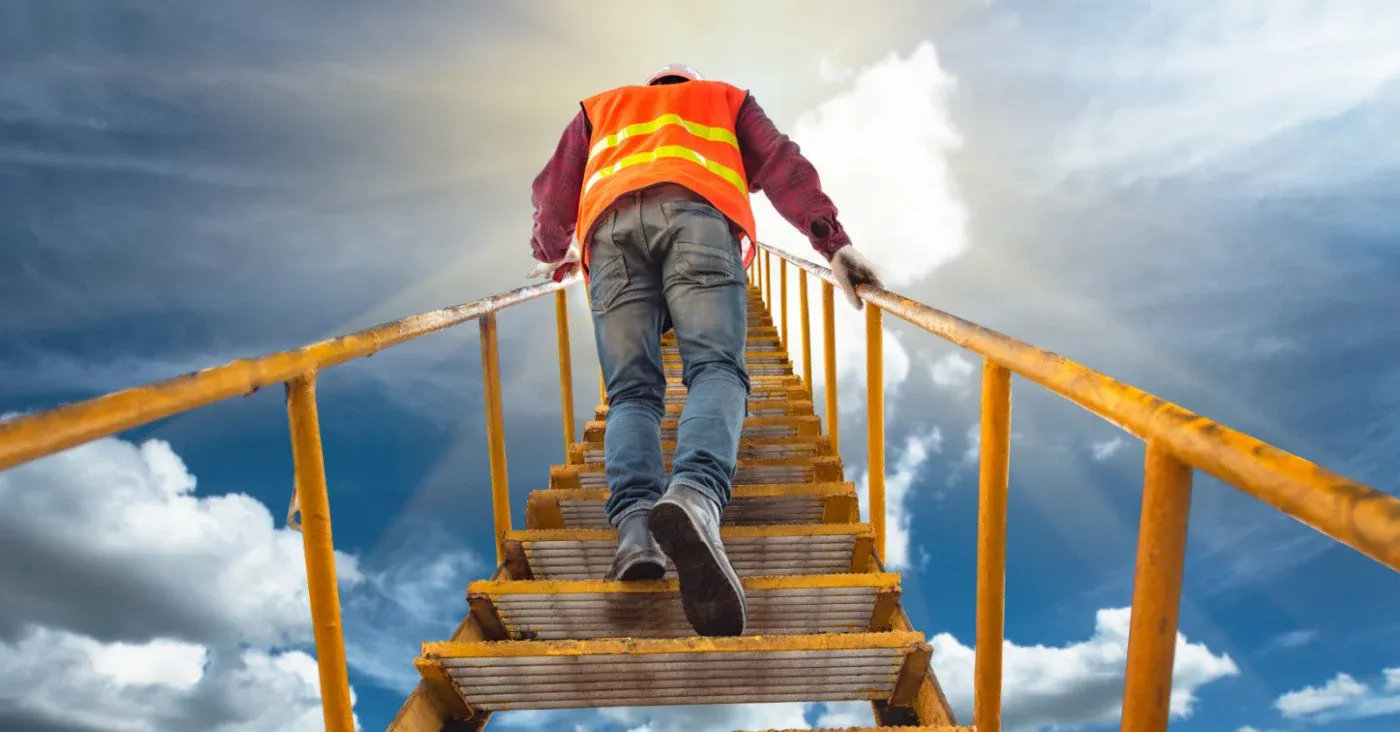 construction worker climbing stairway into sky