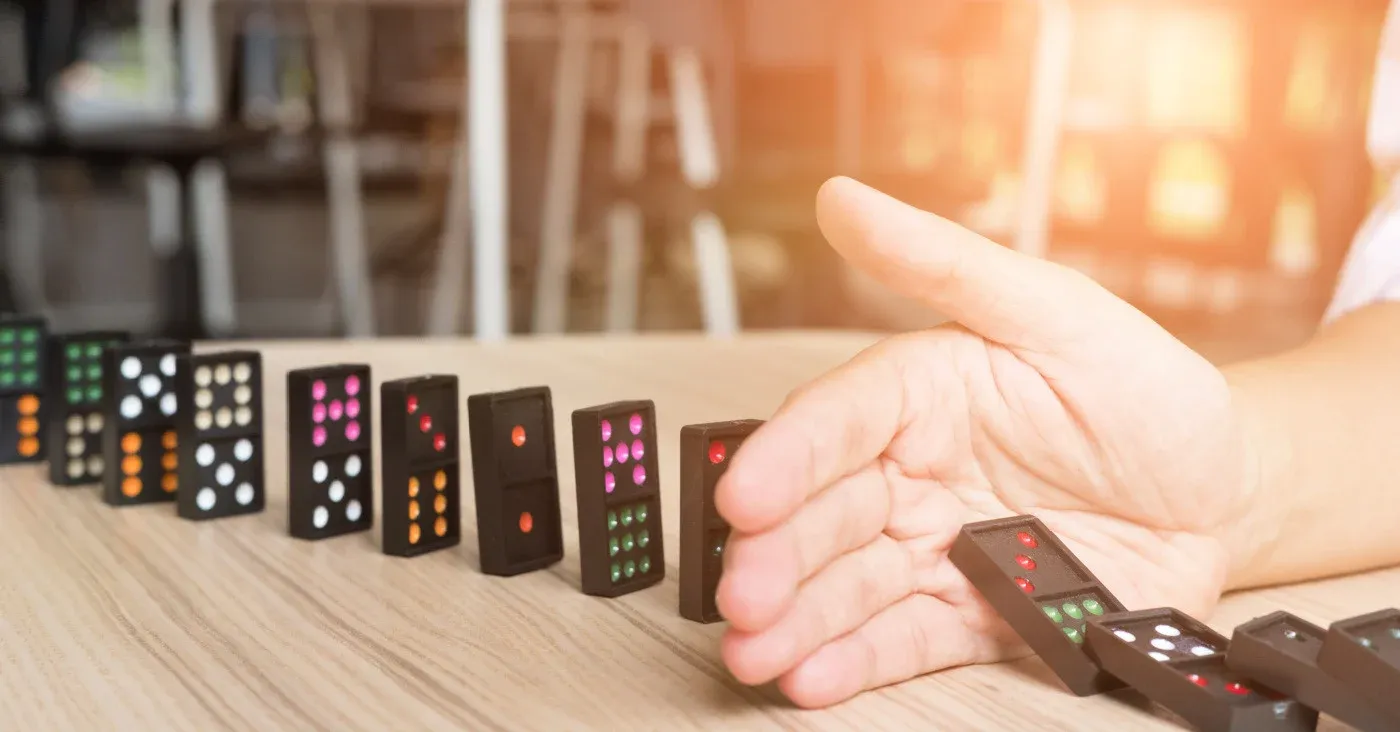 hand stopping line of falling dominoes