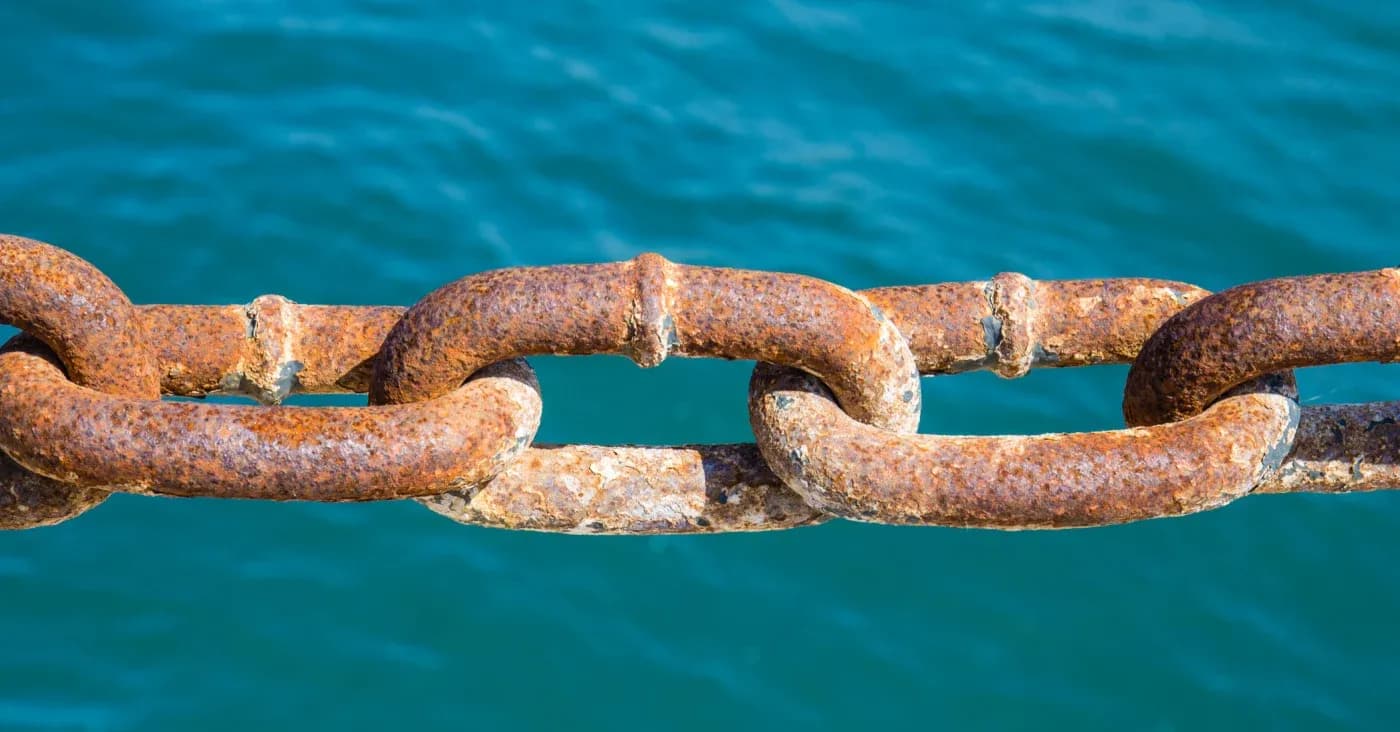 rusty chain links near open body of water